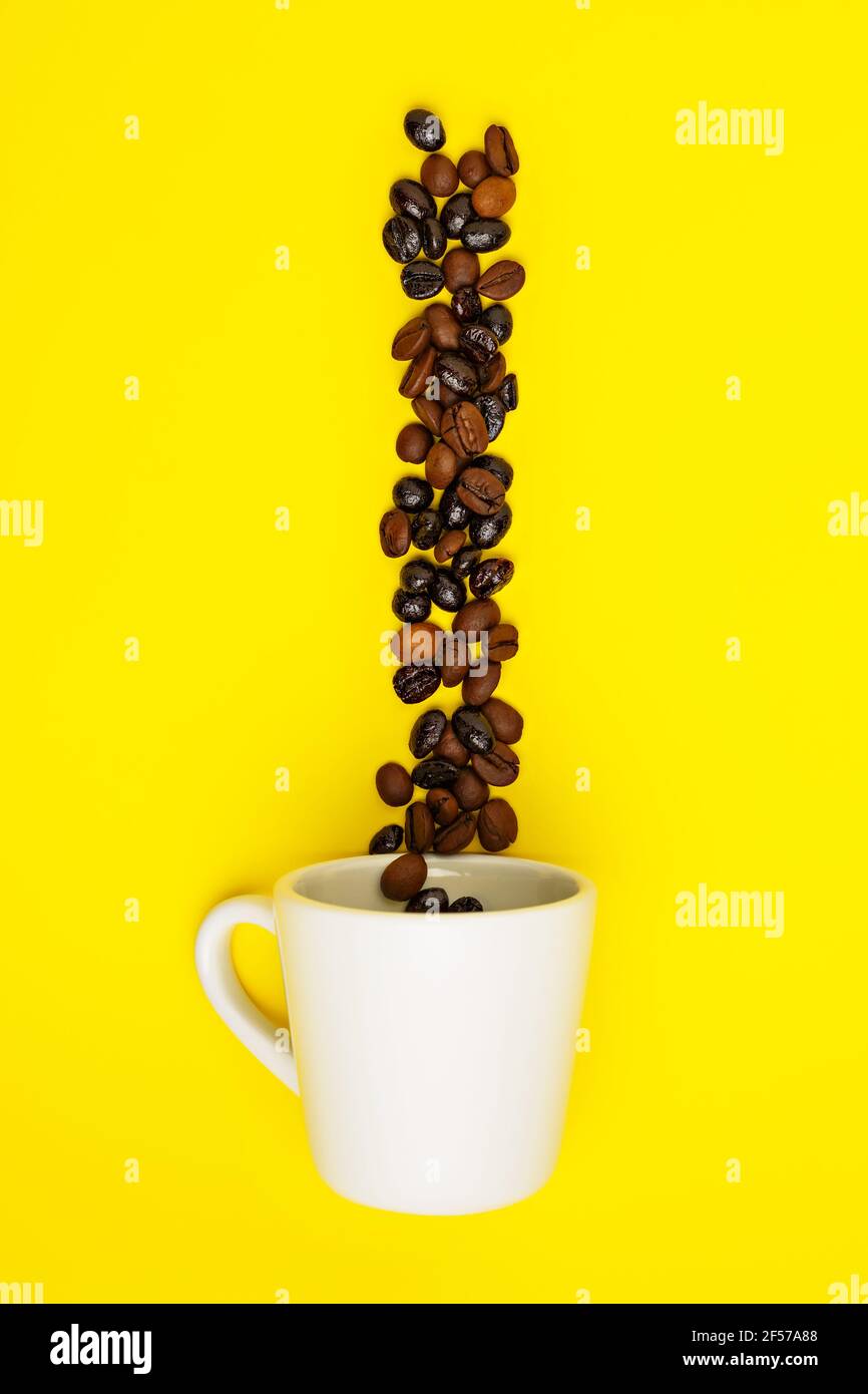 Coffee beans falling into a white cup on yellow background Stock Photo ...