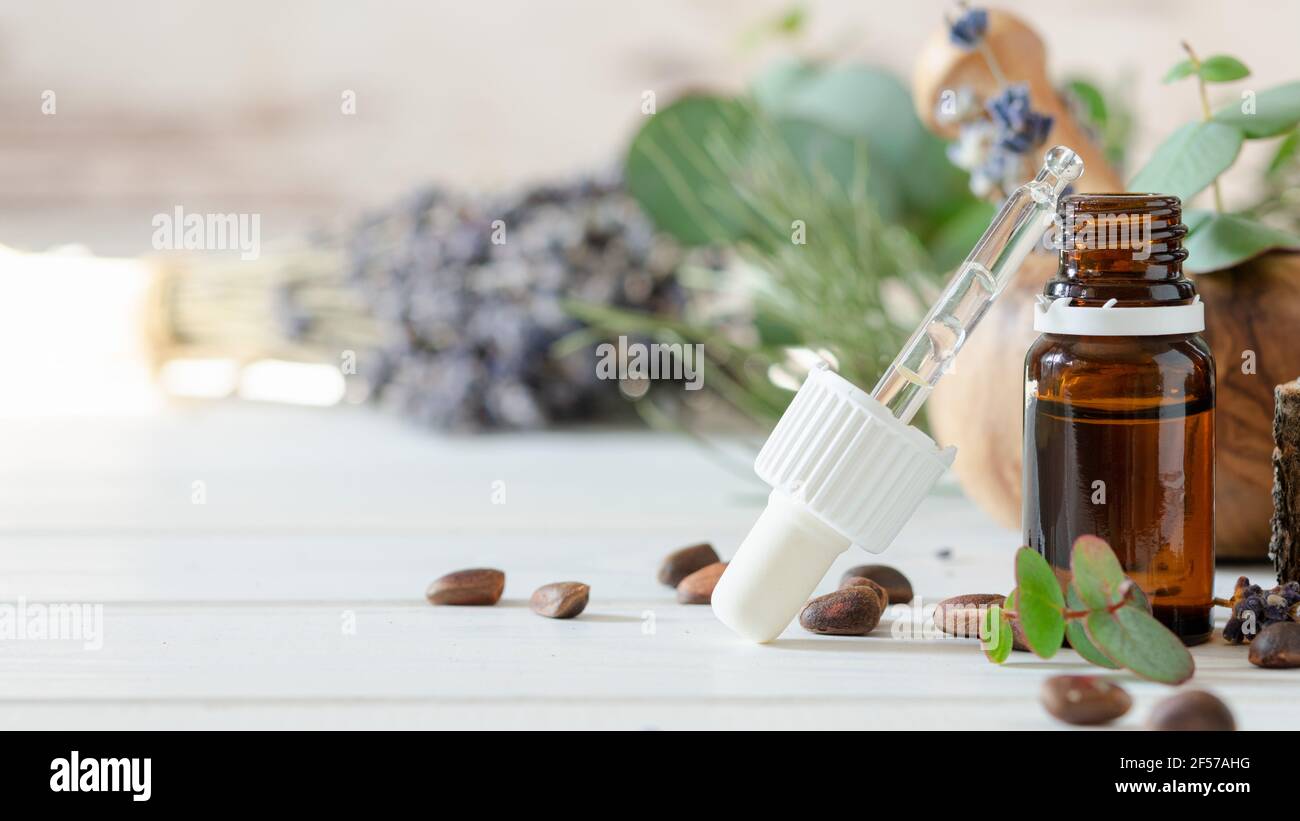 organic cosmetics concept, glass bottle with oil, pipette and lavander flowers, eucaliptus on light wooden background Stock Photo
