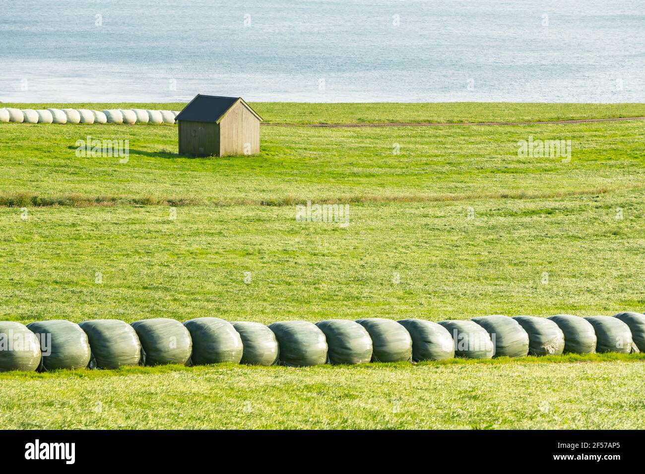 Rural scene with farm field and hay stacks Stock Photo