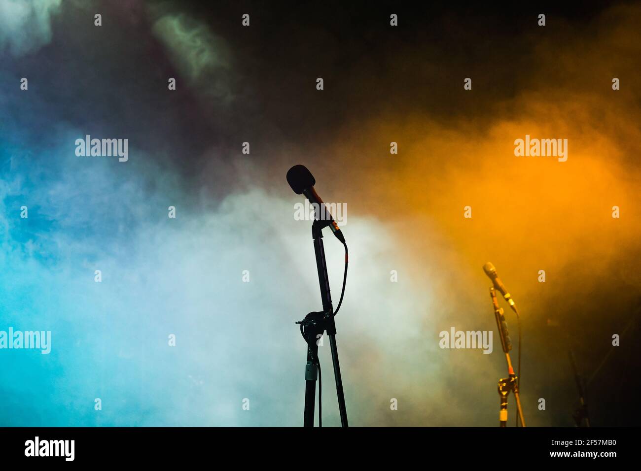 Silhouette of a microphone on an empty stage with coloured lighting and smoke effects Stock Photo