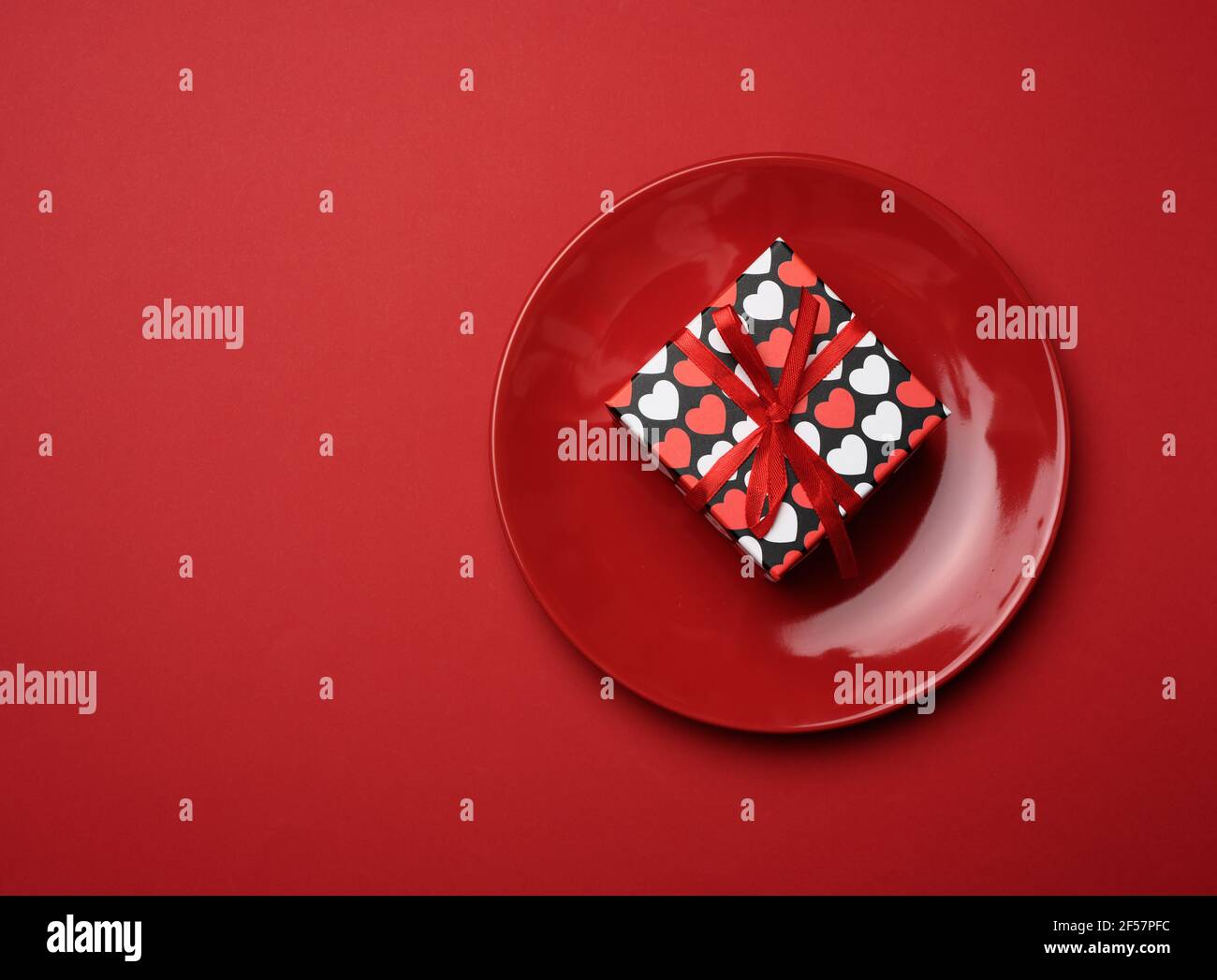 square cardboard box tied with a silk red ribbon lies in a round ...