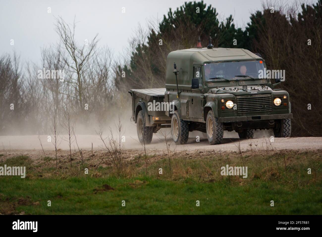 army land rover defender speeding along a dusty stone track on salisbury plain wiltshire Stock Photo