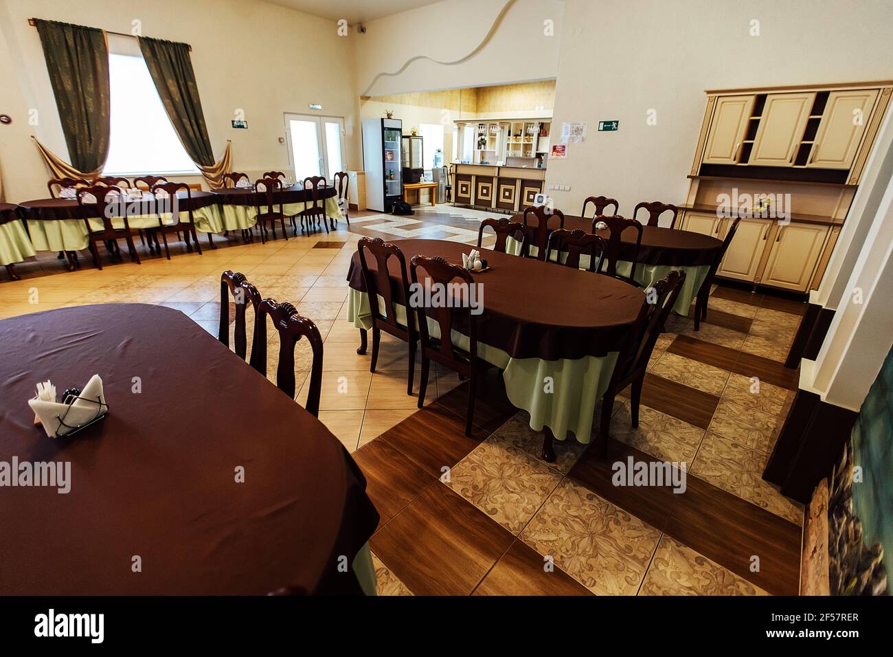 a set table in the restaurant. the cafe hall is waiting for guests for the holiday. clean tablecloth and dishes without food Stock Photo