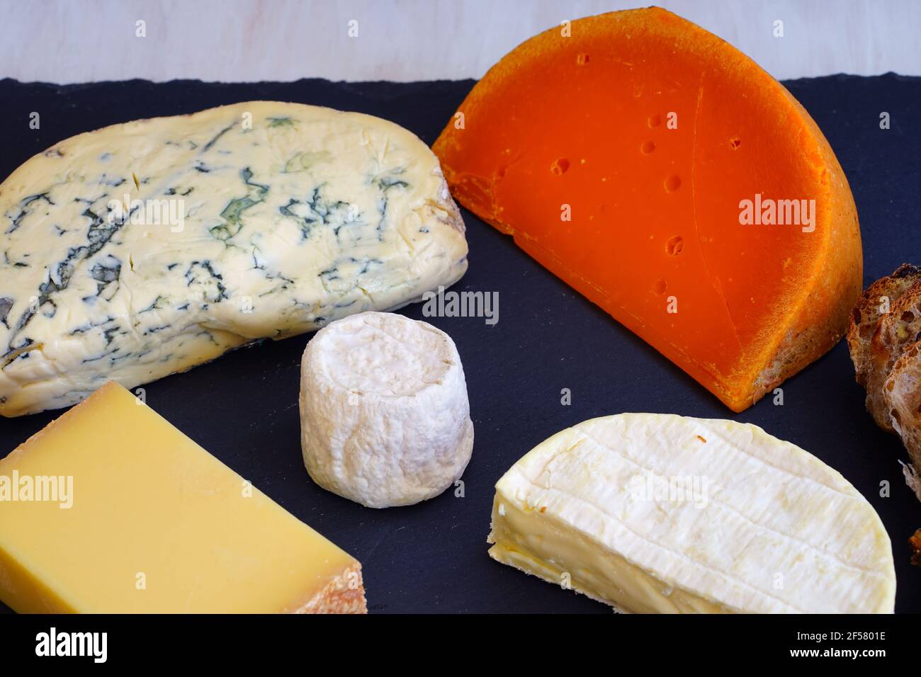Cheese platter with comte,fourme,goat cheese crottin, camembert and orange mimolette cheese on a slate board Stock Photo