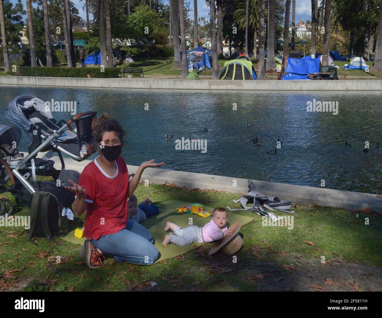 Los Angeles, United States. 24th Mar, 2021. Awoman tends to her twins in  the shadow of a homeless encampment at Echo Park Lake in Los Angeles on  Monday, March 23, 2021. The
