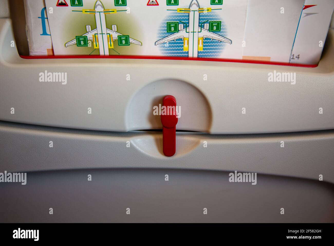 Folded Tray Table And Safety Card In The Back Of An Airplane Seat In