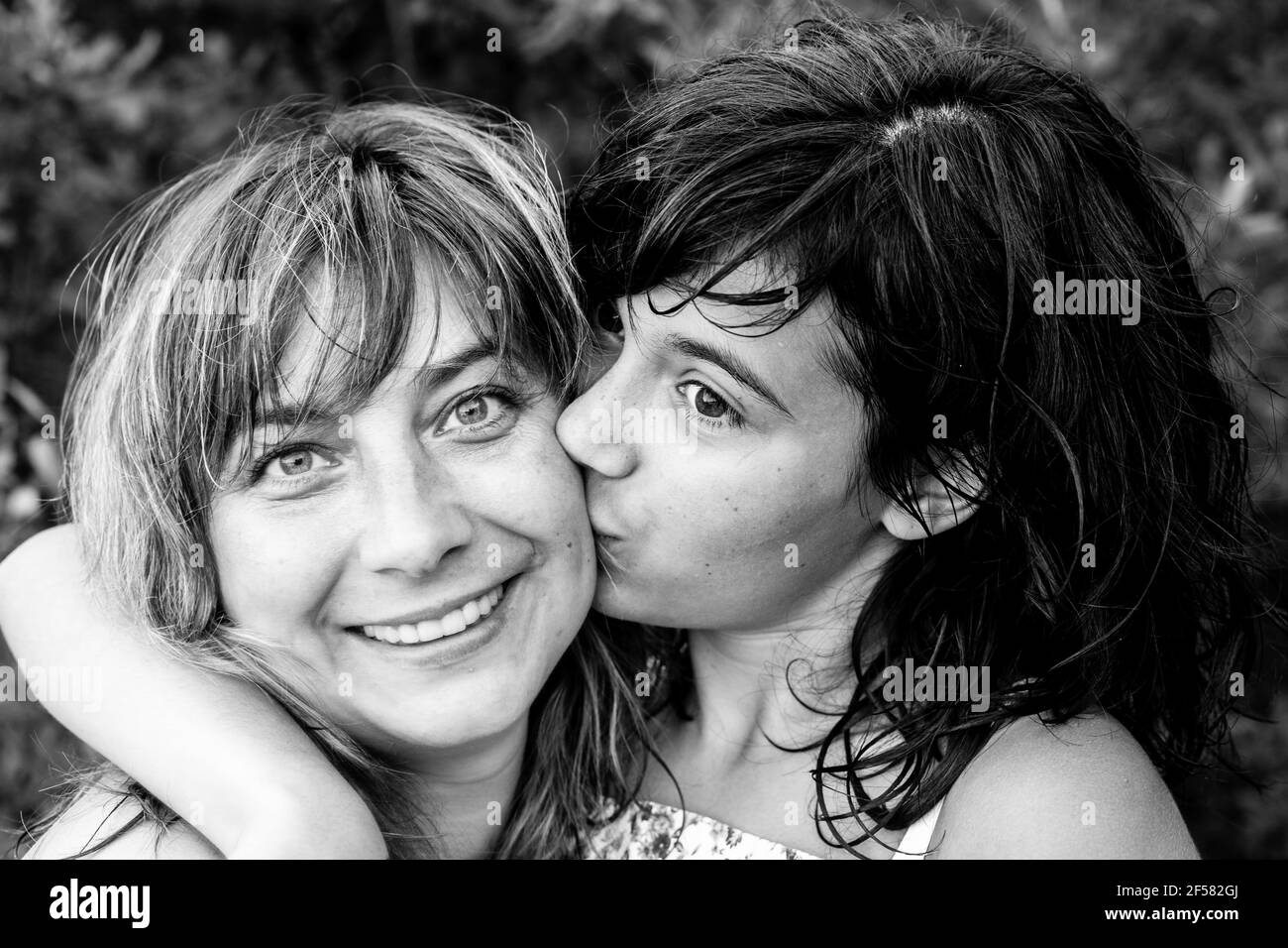 Portrait of woman kissing her daughter. Black and white photo. Stock Photo