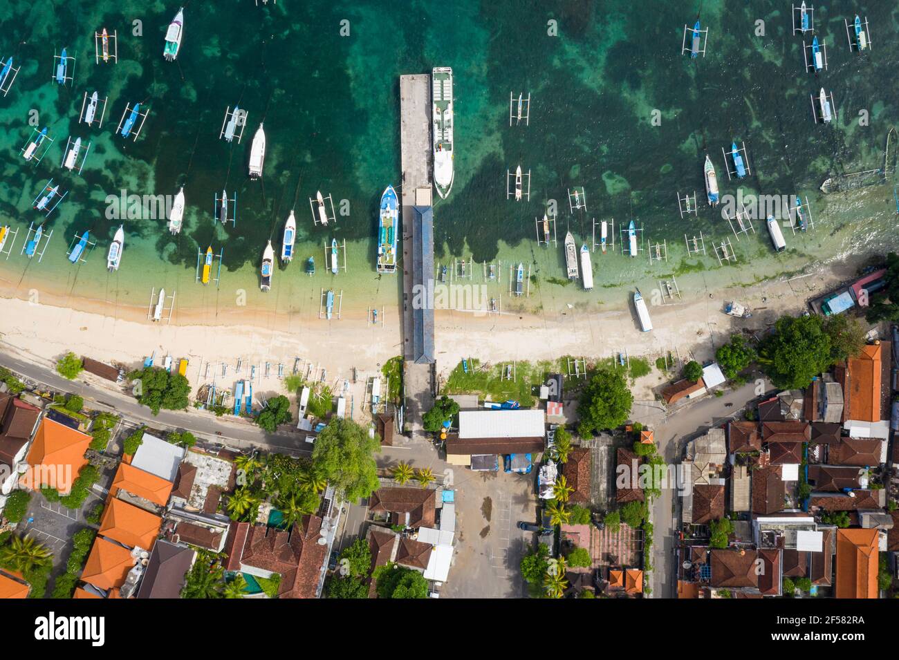 Top down aerial viewf of the idyllic Padangbai village, beach and town in eastern Bali, Indonesia.. The jetty is for speed boat to the Gili island and Stock Photo