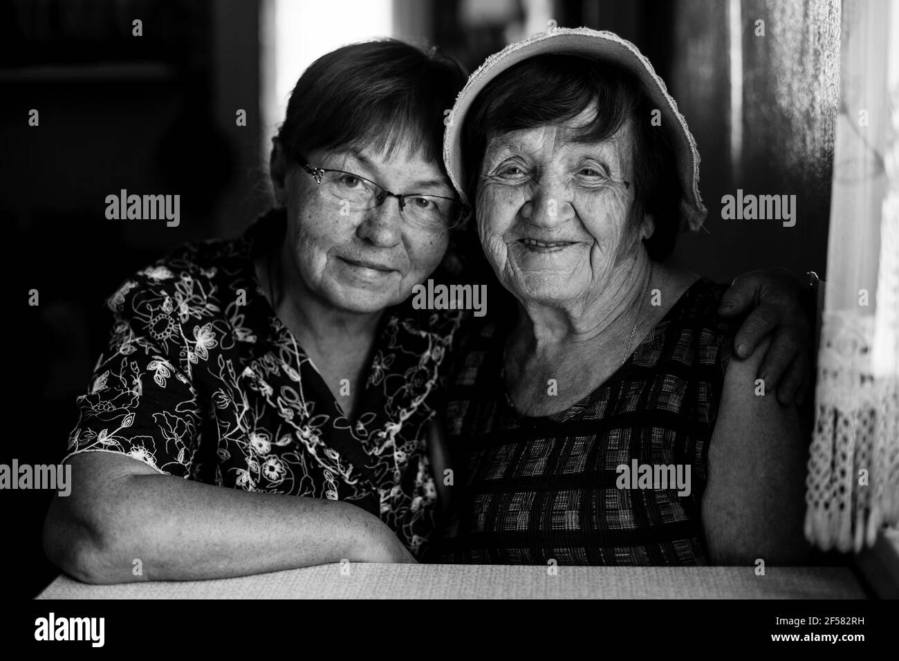 Pld woman and her mature daughter posing for portrait. Black and white ...