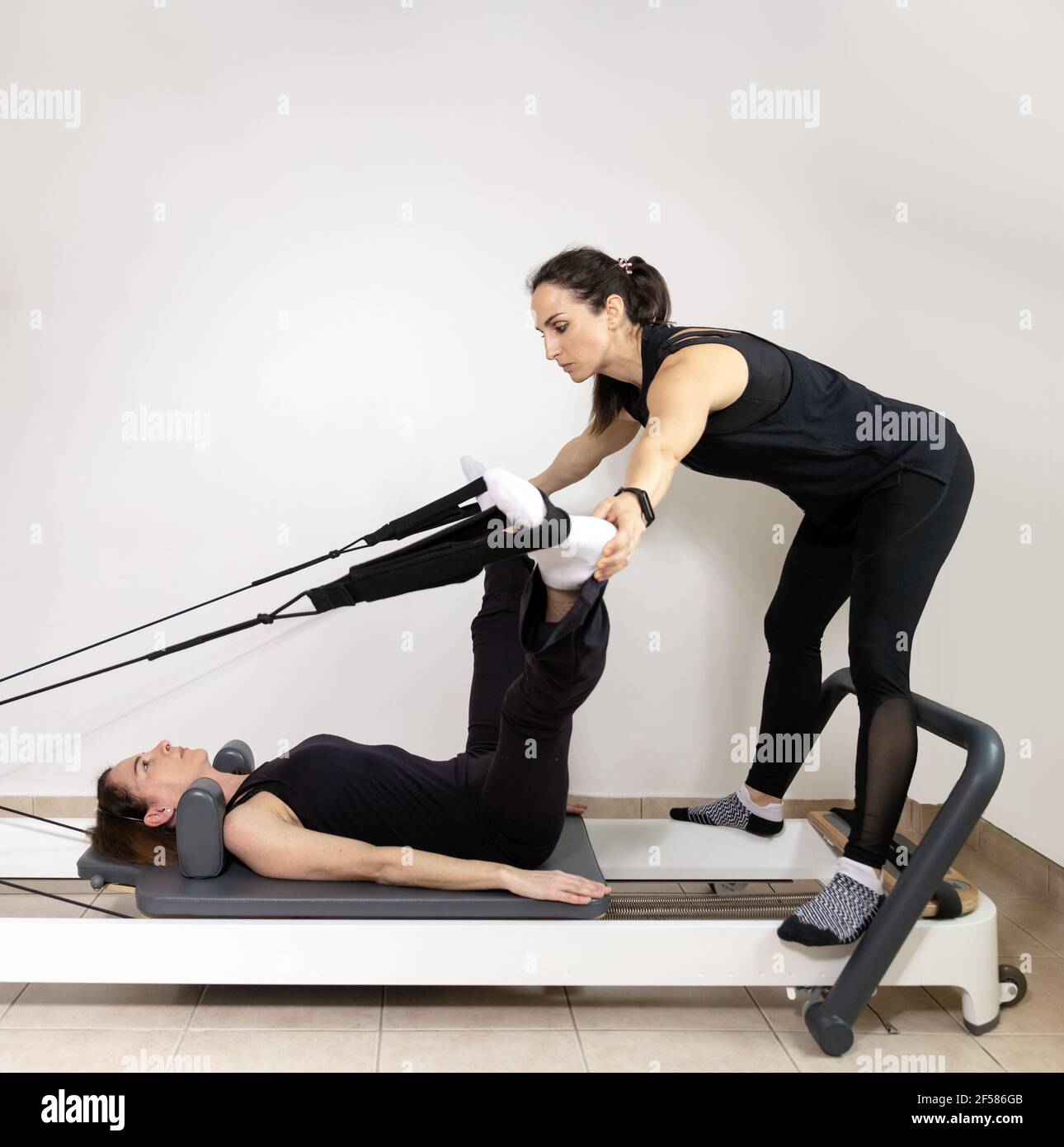 A woman practicing exercises with a pilates personal trainer. Stock Photo