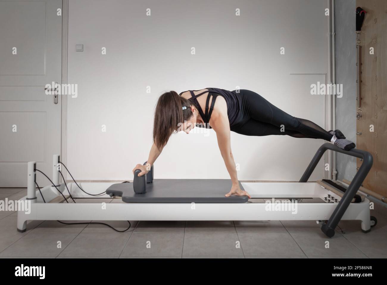 A woman doing pilates exercises on a reformed bed. Stock Photo