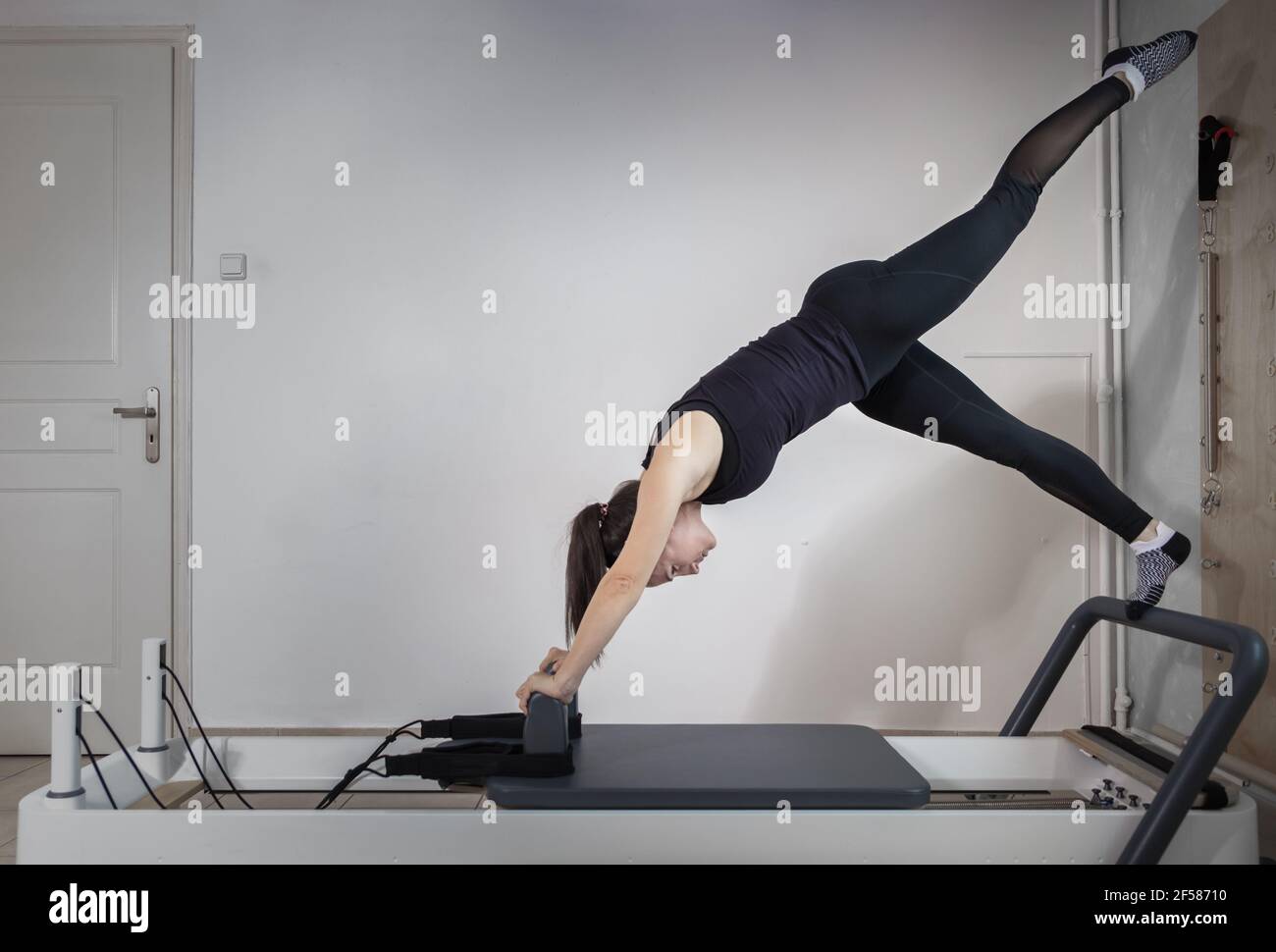 A woman doing pilates exercises on a reformed bed Stock Photo - Alamy