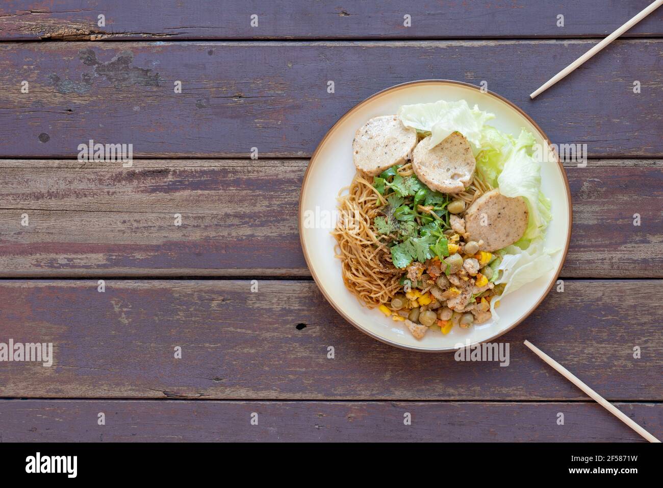 Dry noodles, served with vegetables, salad, Vietnamese sausage and corn fried pork. Top view. Stock Photo
