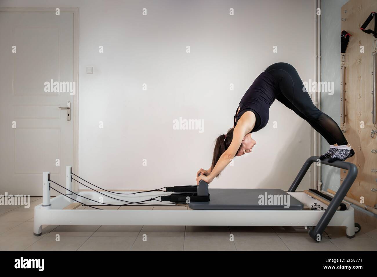 A woman doing pilates exercises on a reformed bed. Stock Photo