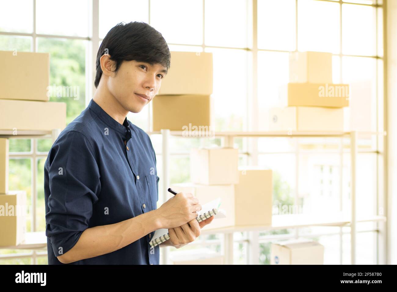 Young man starts small business (SME) by delivering products packed into boxes through a logistics system from home office, package delivery, online m Stock Photo