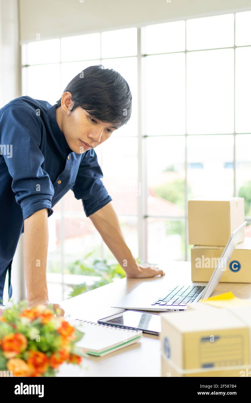 Young man starts small business (SME) by delivering products packed into boxes through a logistics system from home office, package delivery, online m Stock Photo