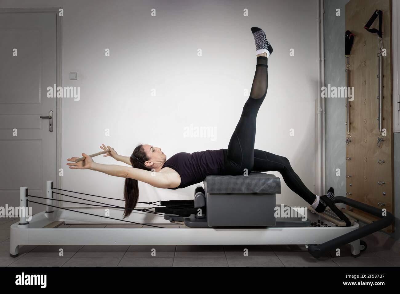 A woman doing pilates exercises on a reformed bed. Stock Photo