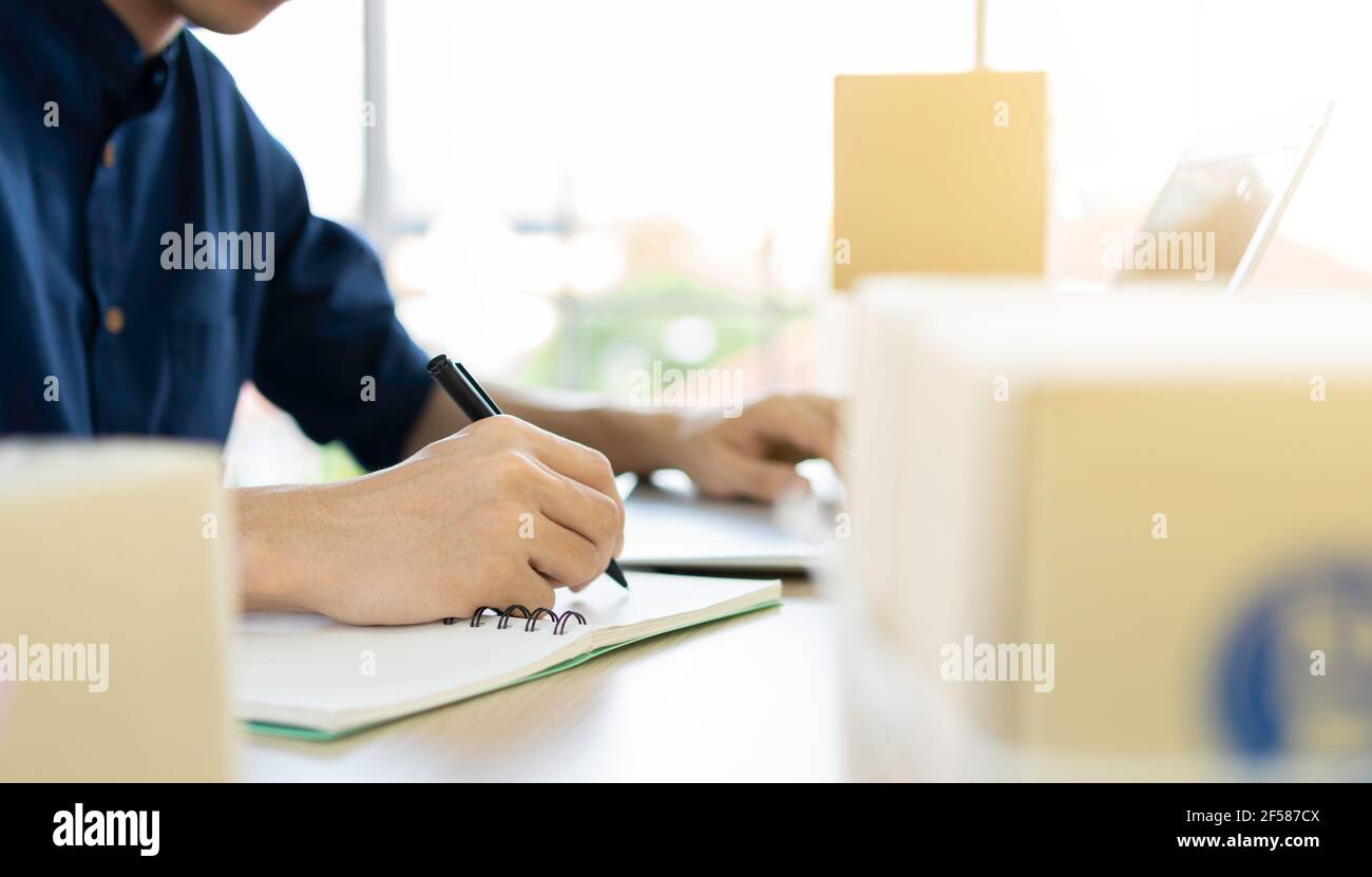 Young man starts small business (SME) by delivering products packed into boxes through a logistics system from home office, package delivery, online m Stock Photo