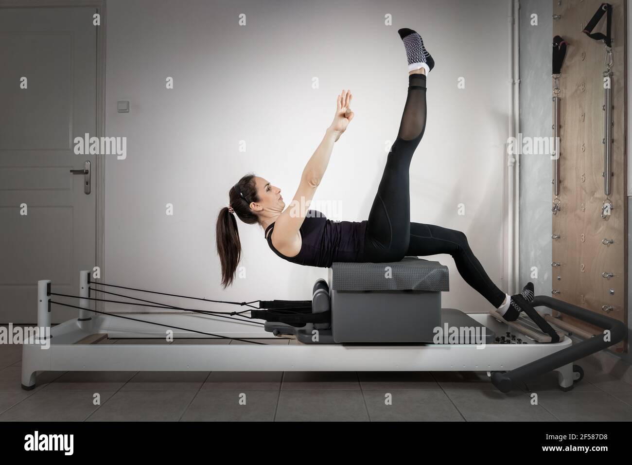 A woman doing pilates exercises on a reformed bed Stock Photo - Alamy