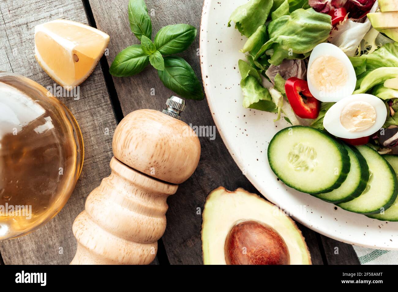 Healthy eating concept flat lay. Mediterranean diet, plate with lettuce salad leaves, quail eggs, avocado half with kernel, cucumber slices, pepper, b Stock Photo