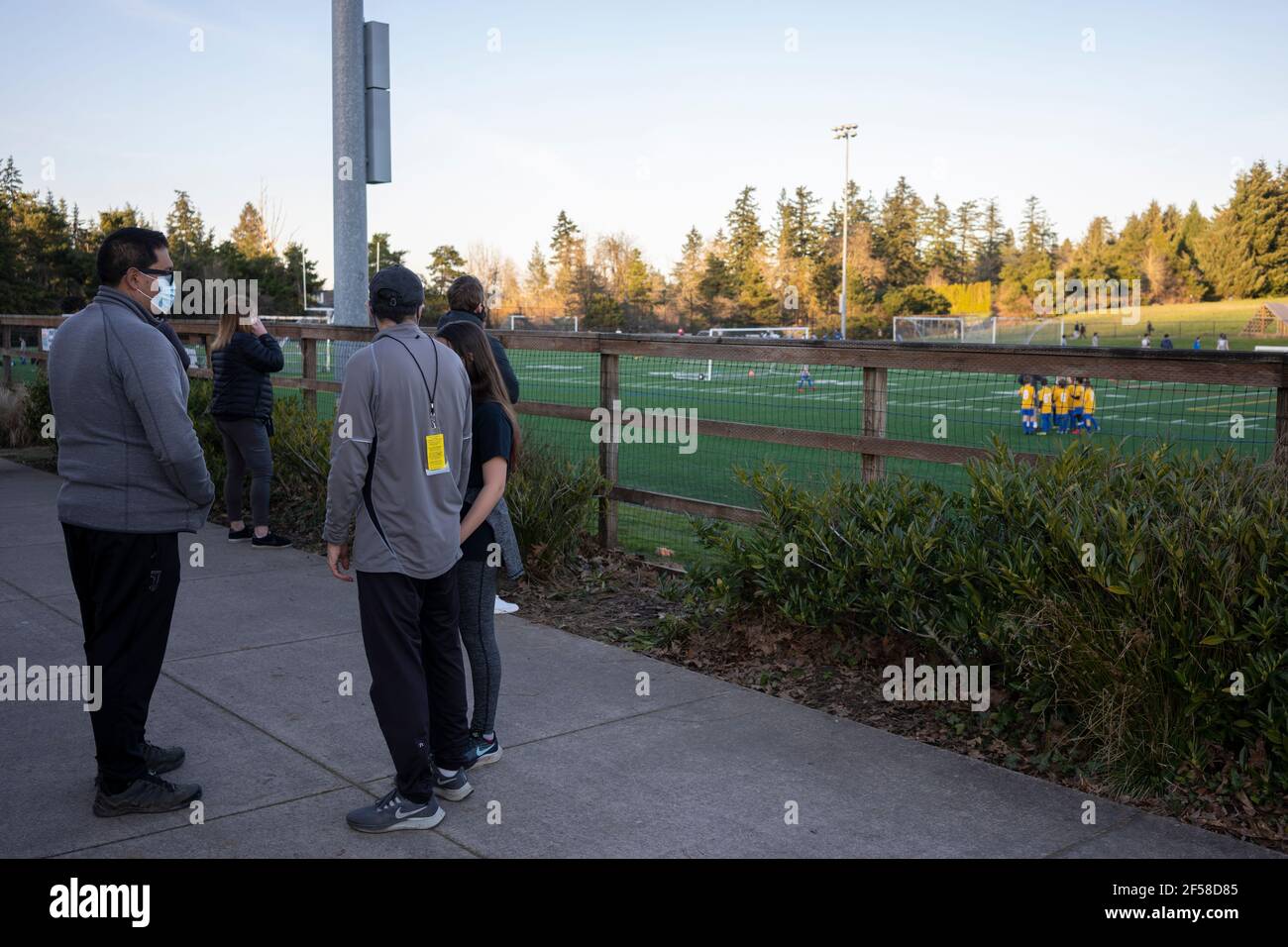 Kids play soccer in a training camp in Lake Oswego, Oregon, on Thursday, March 11, 2021, while masked parents wait outside as spring approaches amid ... Stock Photo