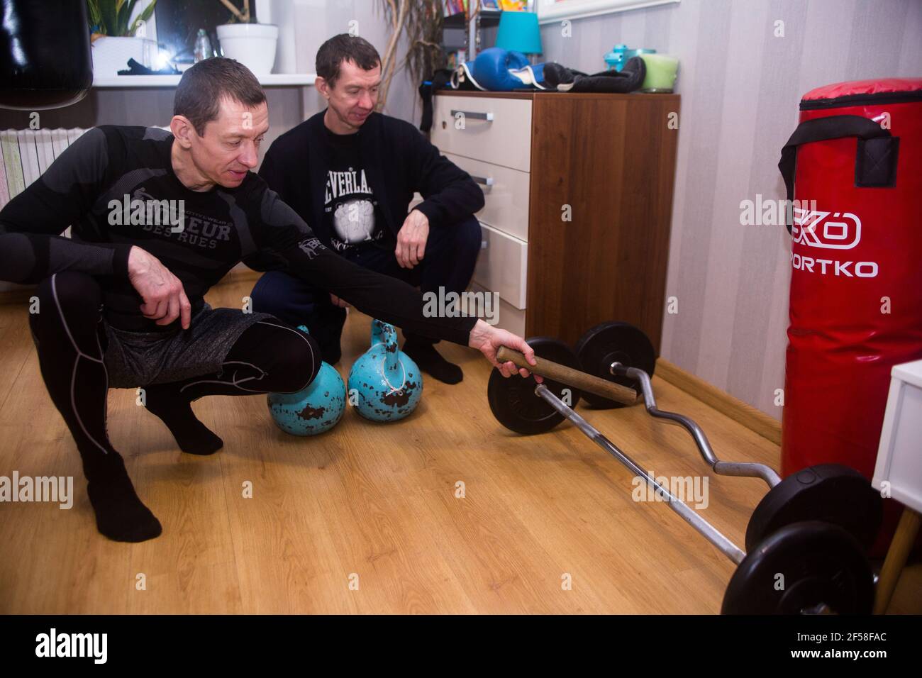 Twin brothers Alexander and Yury Yarmolenko European kick boxing champions show their coach Alexander Kartashov relic equipment at their home museum Stock Photo