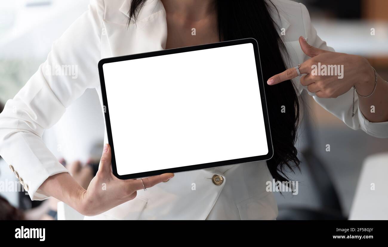 Businesswoman shows the digital tablet with blank screen in a front view shot. Stock Photo