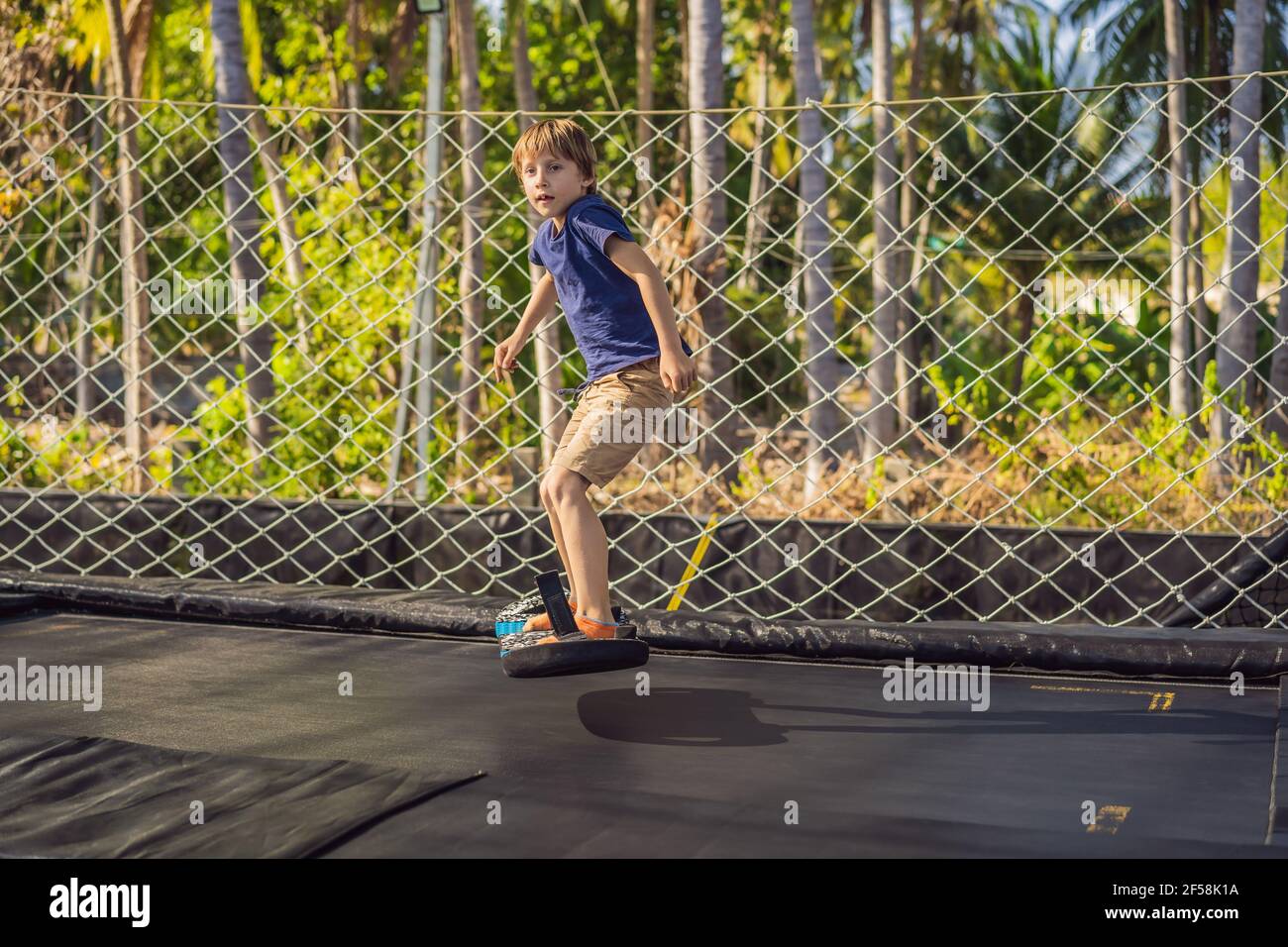 Happy boy on a soft board for a trampoline jumping on an outdoor trampoline,  against the backdrop of palm trees. The trampoline board is like a Stock  Photo - Alamy