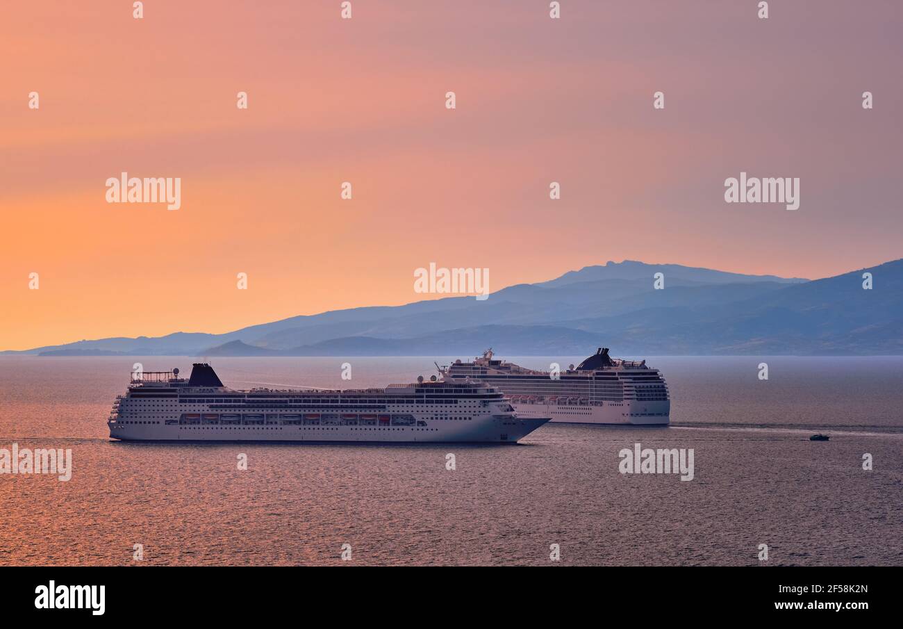 Two big tourist cruise liners manoeuvre in harbor. Beautiful sunset sky and distant hazy islands. Sea voyage, comfort, adventure, romantic honeymoon. Stock Photo