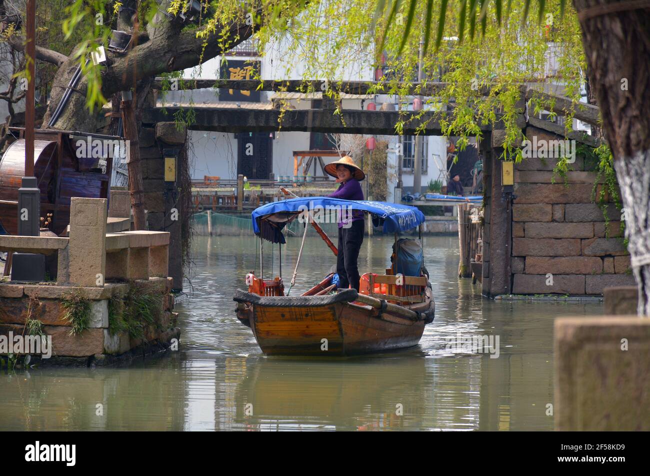 A lady navigates her tourist boat through the waterway of the top rated Chinese scenic area of Zhouzhuang in Jiangsu province. Stock Photo