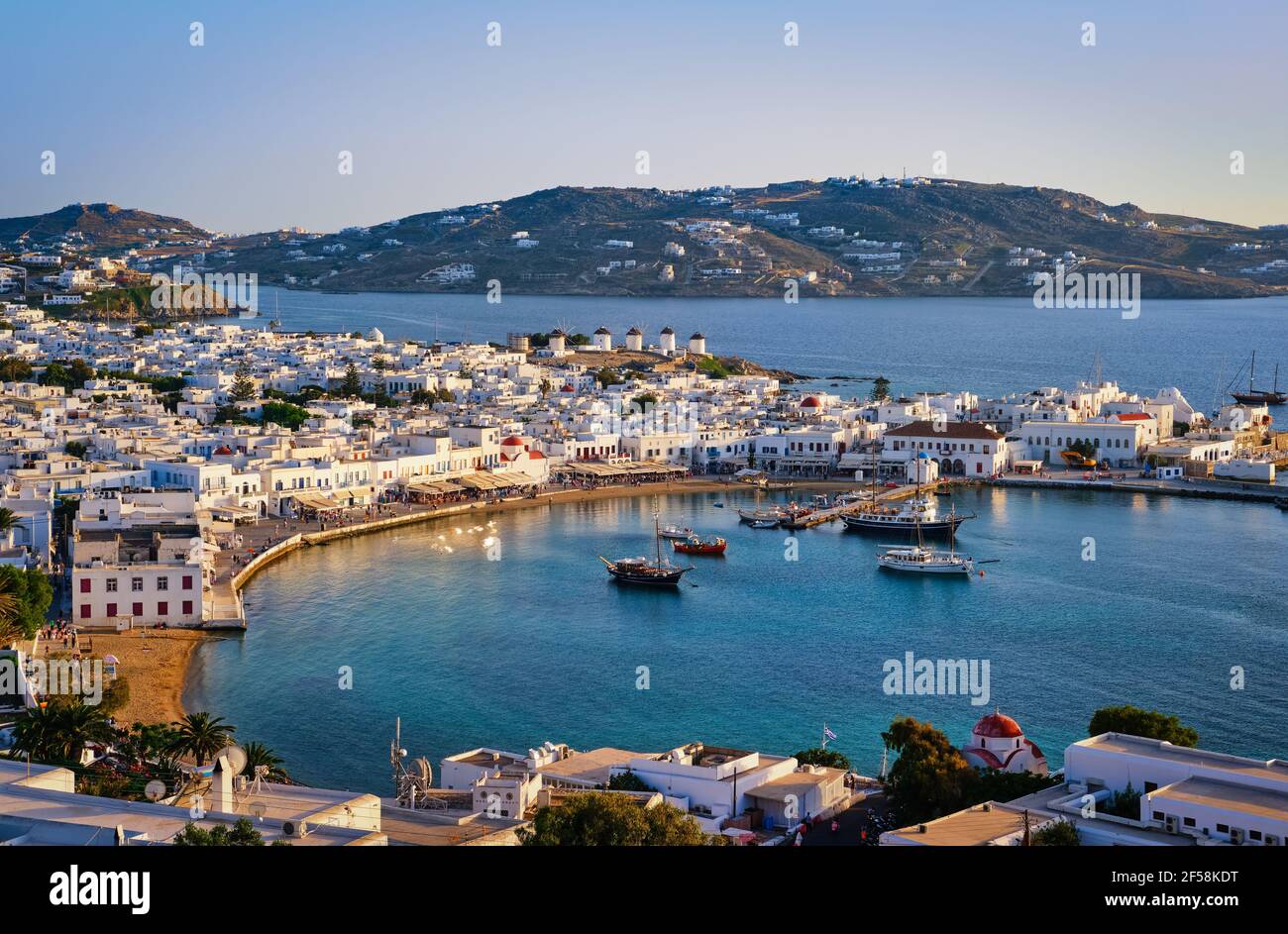 Beautiful sunset view over town of Mykonos, Greece and port. Golden hour, harbor, cruise ships, whitewashed houses. Vacations, Mediterranean lifestyle Stock Photo