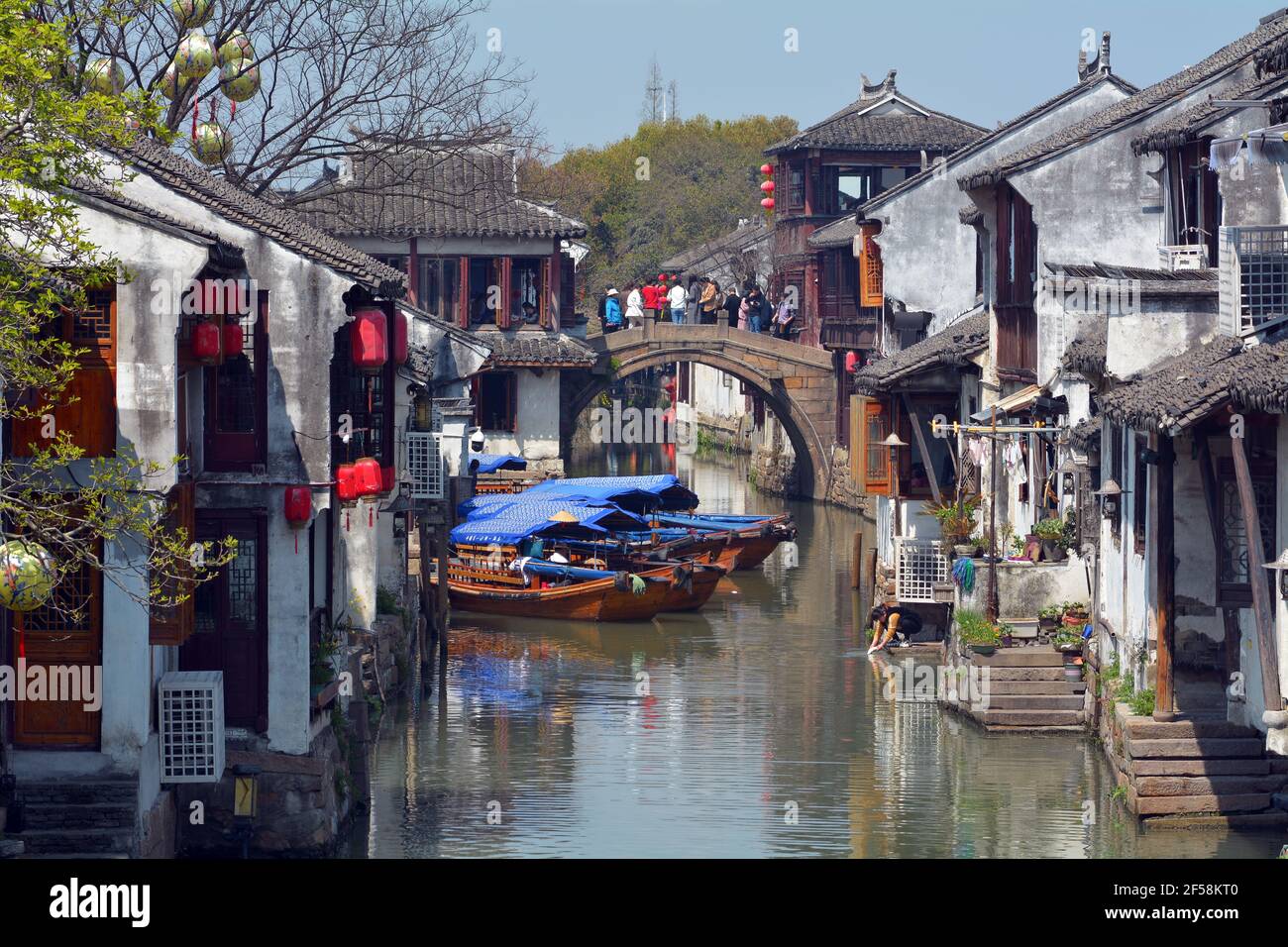 Zhouzhuang scenic area in Jiangsu,China. Tourists take photos on a stone bridge while locals do their washing in the canal. Stock Photo