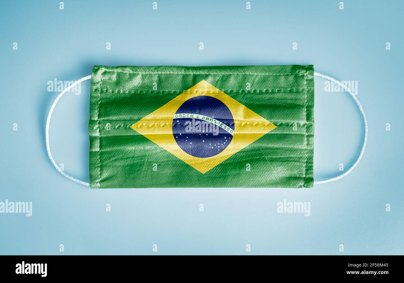 Covid-19 Coronavirus protection concept: Medical disposable face mask with Brazil flag on blue background. WHO recommends usage of mask for safety. Stock Photo