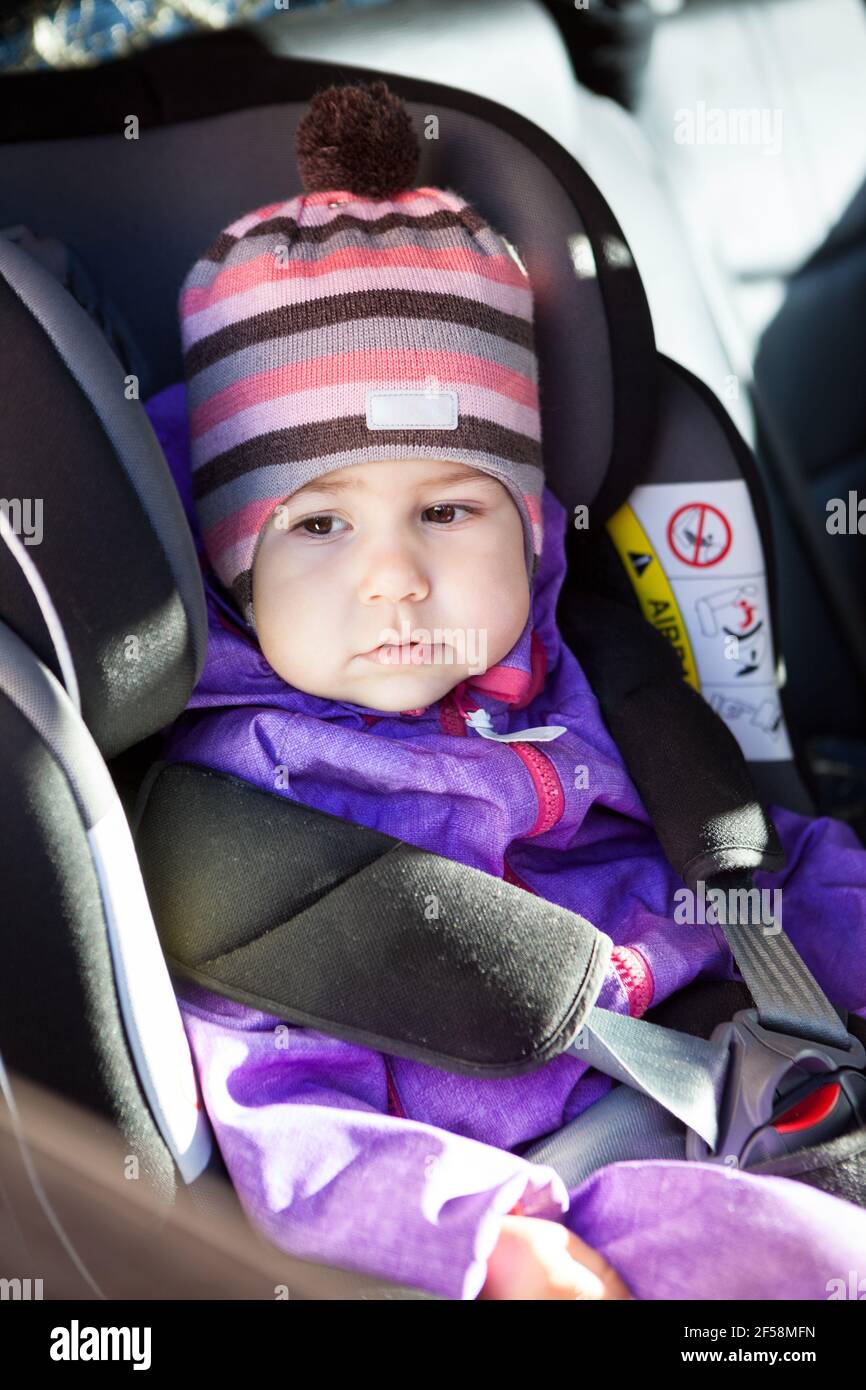 Portrait of young kid wearing winter clothing sitting in baby car seat with adjustable headrest Stock Photo