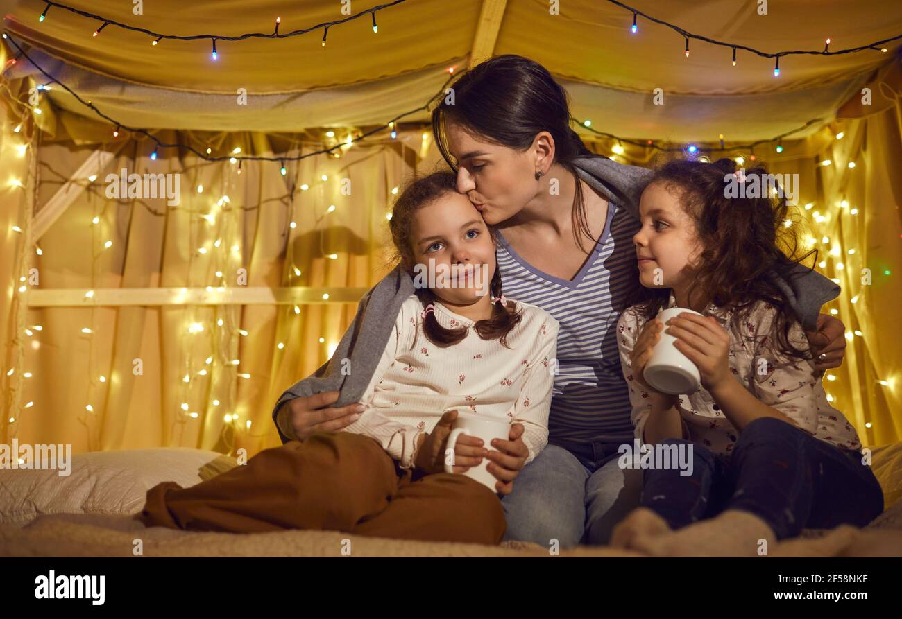 Mother kissing loving children while spending time together before bedtime Stock Photo