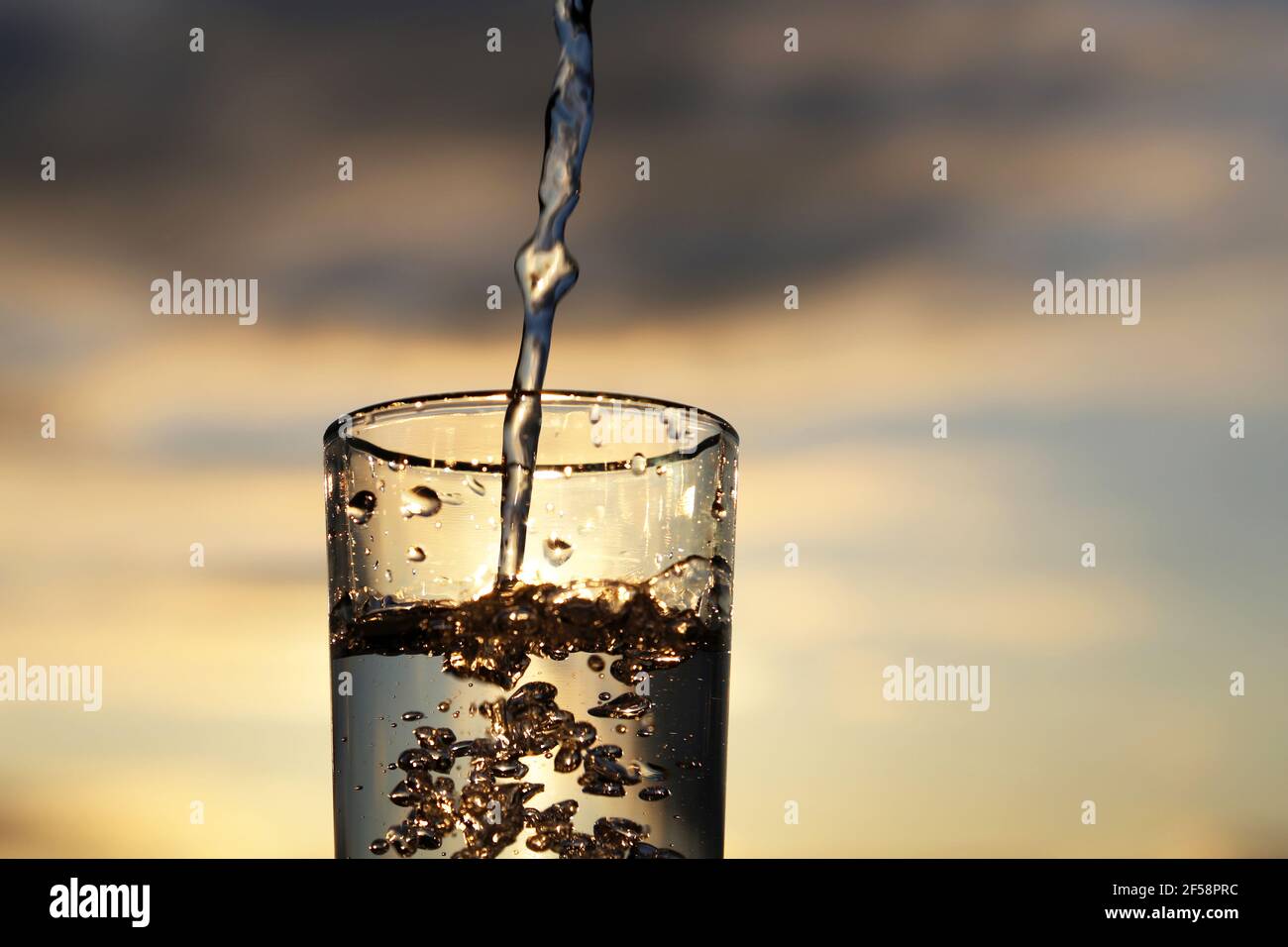 Clean water pouring into drinking glass on sunset blurred background.  Concept of health and freshness, thirst, water purification Stock Photo -  Alamy
