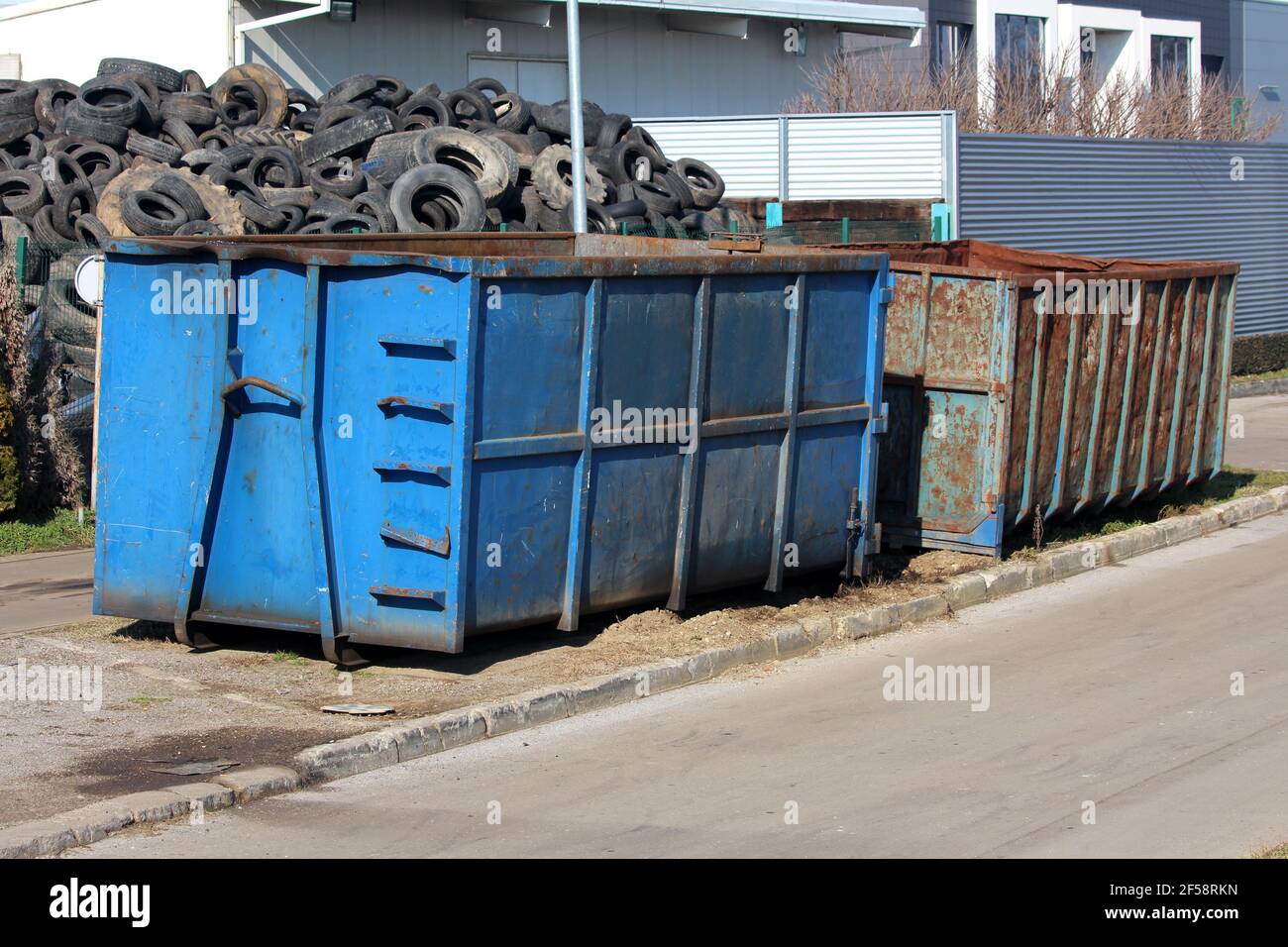 Large pile of used car tyres behind two heavily used industrial