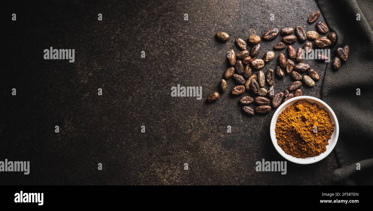 Cocoa powder and cocoa beans in bowl on black table. Top view. Stock Photo