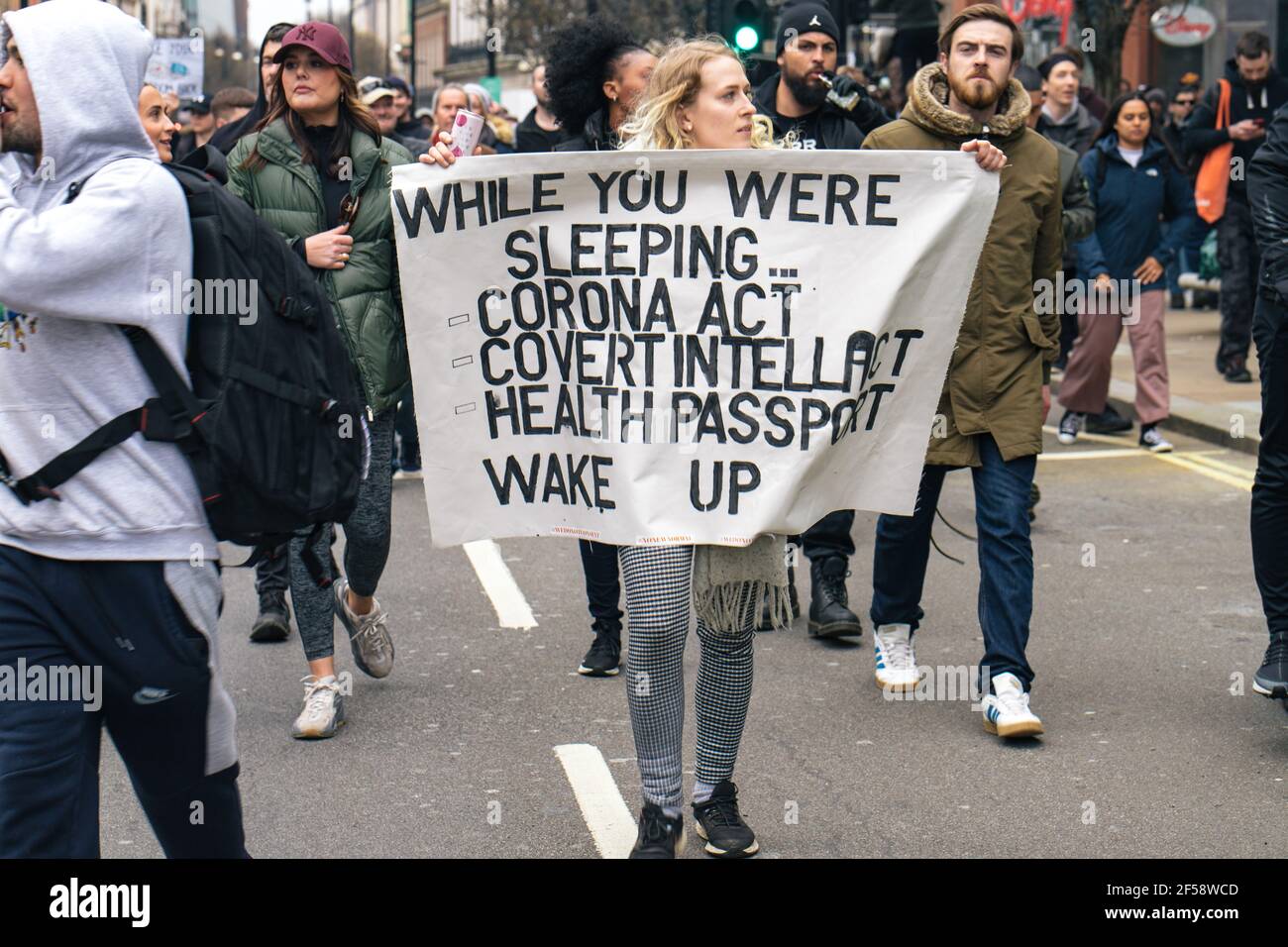 London, UK, 20th March 2021. Around 6000 anti lockdown and anti vaccination protestors and those against the Police, Crime, Sentencing and Courts Bill march in central London. The protest began in Hyde Park with a spate of arrests and an address by Piers Corbyn who is running for London Mayor, marched without trouble through central London and finished with a tense stand off back in Hyde Park between around 200 remaining protestors and riot police. A woman holds a banner urging people to wake up to the governments introduction of the Covid bill and health passports Stock Photo