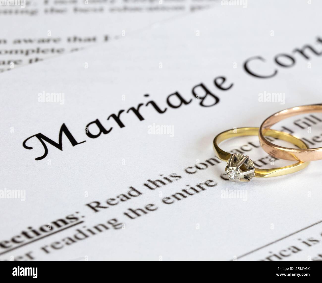 Marriage contract with two golden wedding rings and gold pen, prenuptial agreement, macro close up, sign with signanture,document,agreement concept Stock Photo
