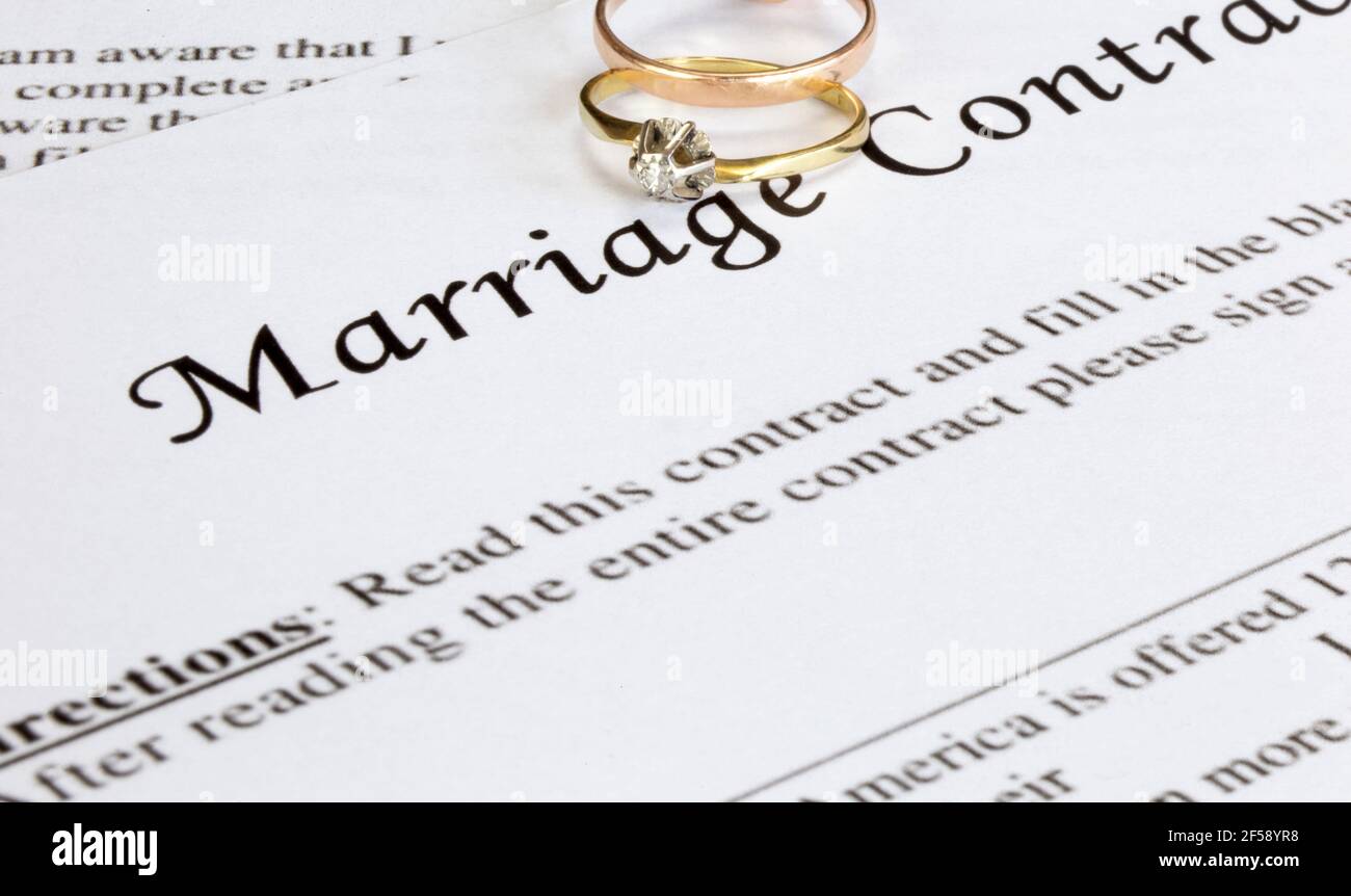 Marriage contract with two golden wedding rings and gold pen, prenuptial agreement, macro close up, sign with signanture,document,agreement concept Stock Photo