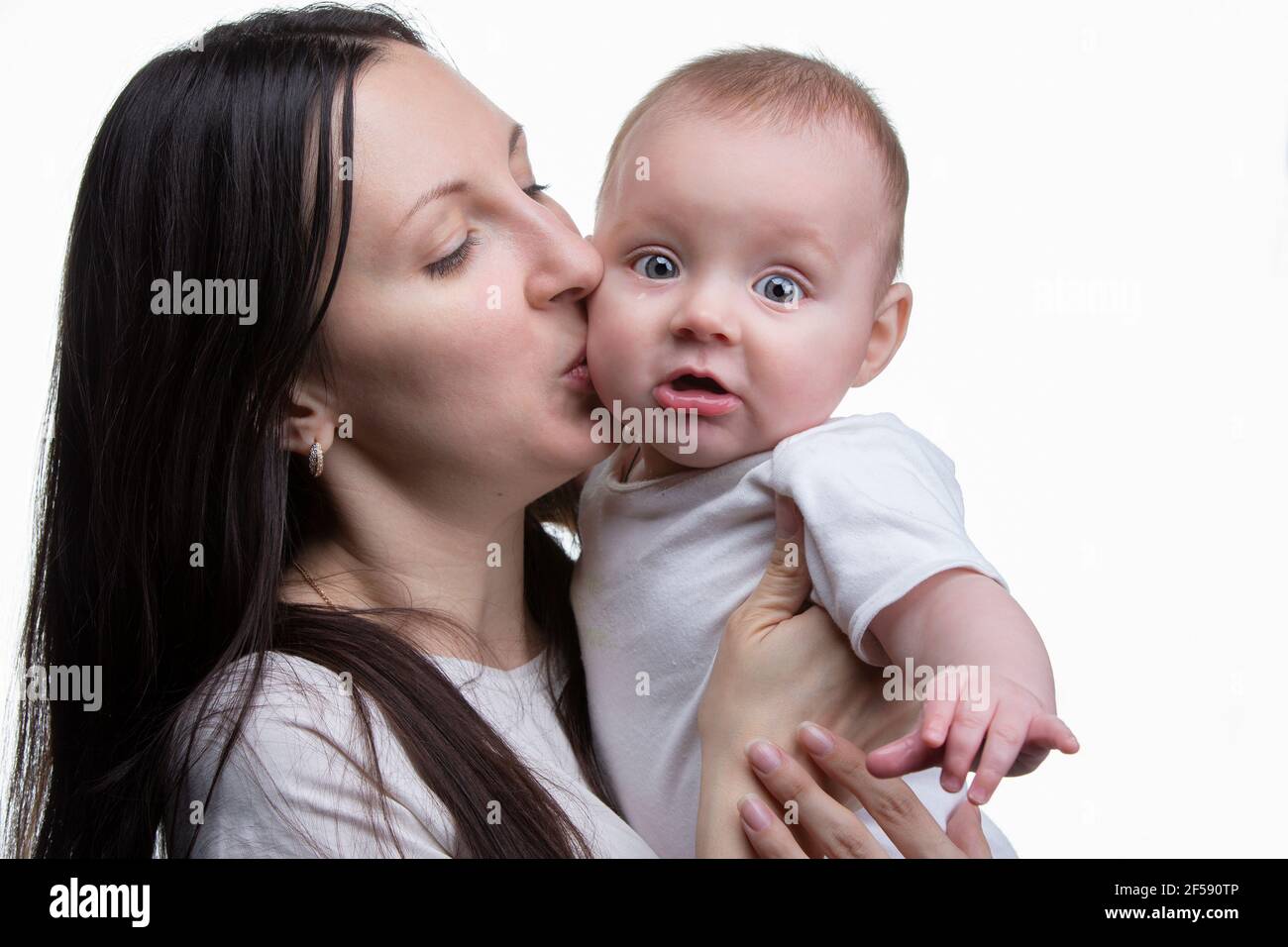 Mom kisses her little son on a light background. Motherhood. Stock Photo