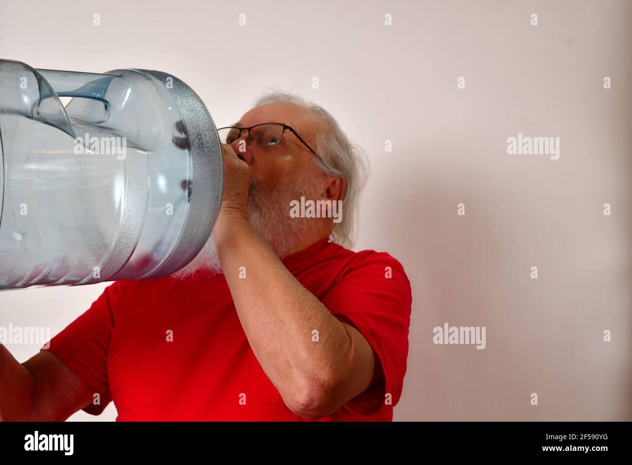 elderly person drinking water from large marked water bottle at home
