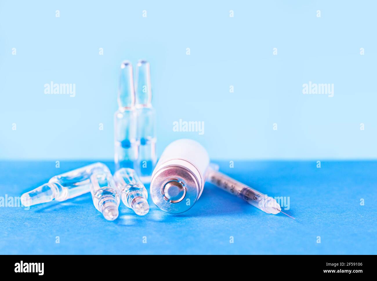 Medical ampoules for injection, vial and syringe on a blue background