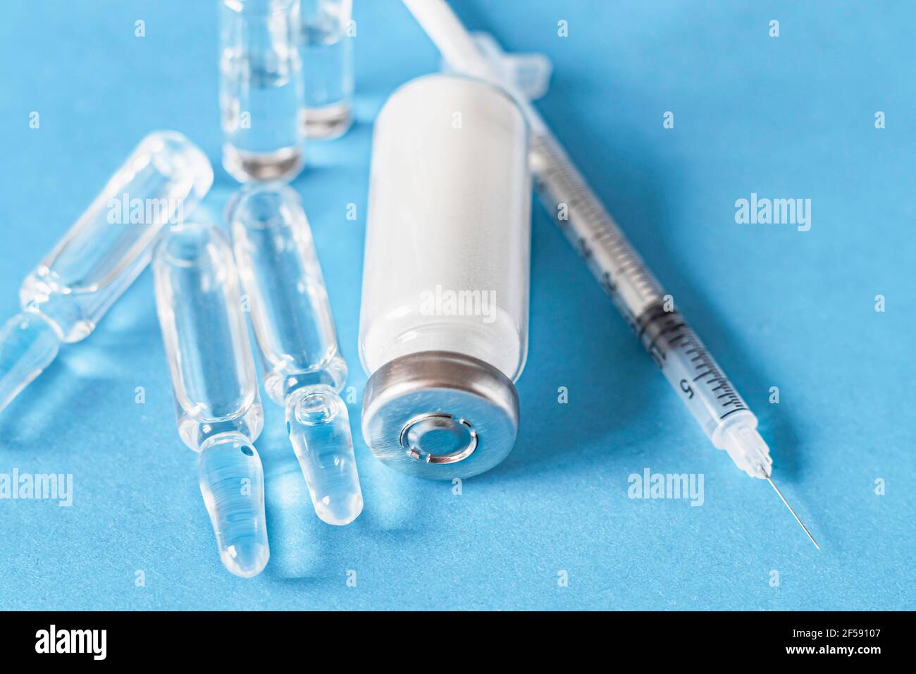 Medical ampoules for injection, vial and syringe on a blue background. Glass ampoules and vials