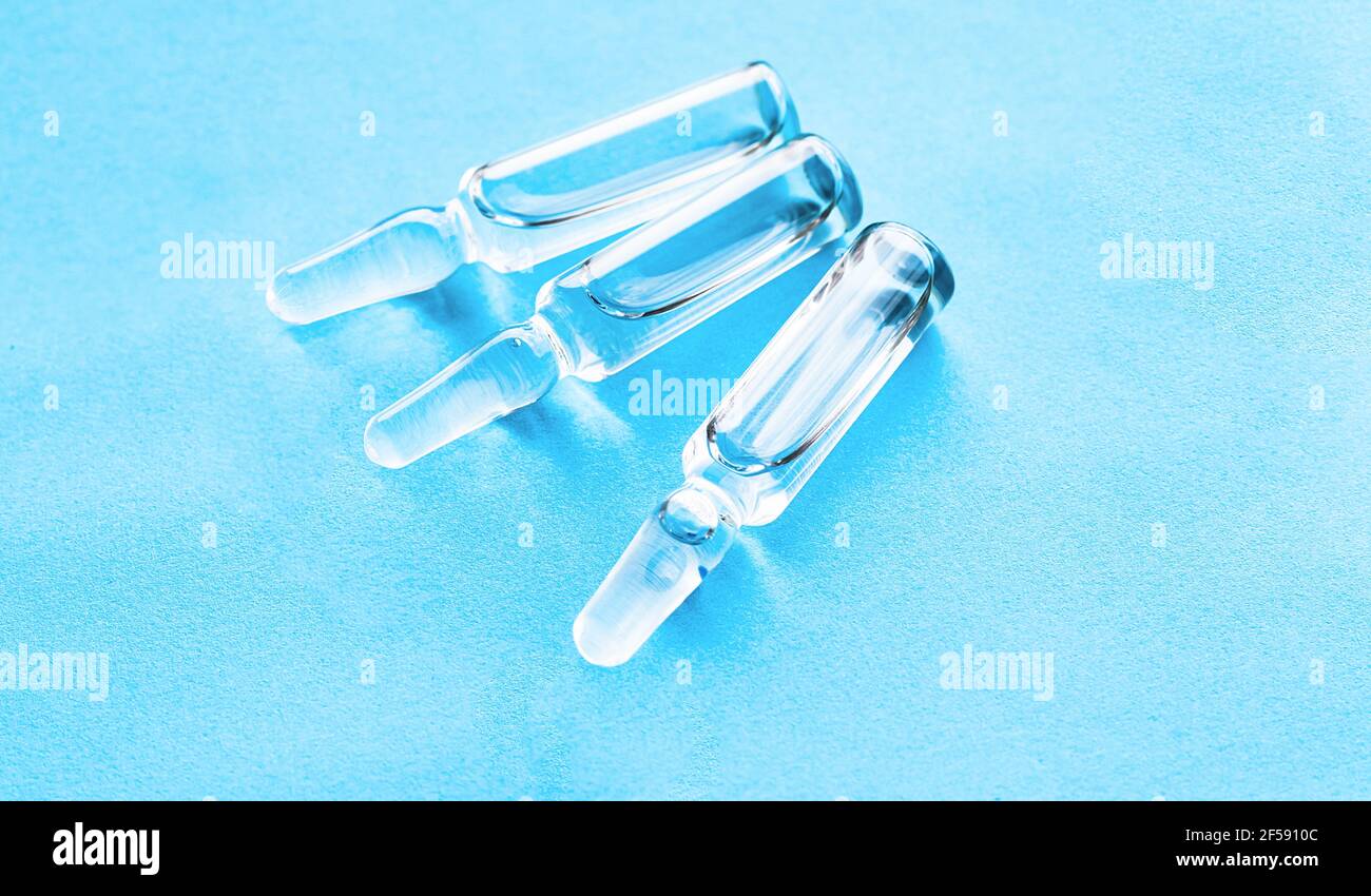 Medical ampoules for injection on a blue background. Scattered glass