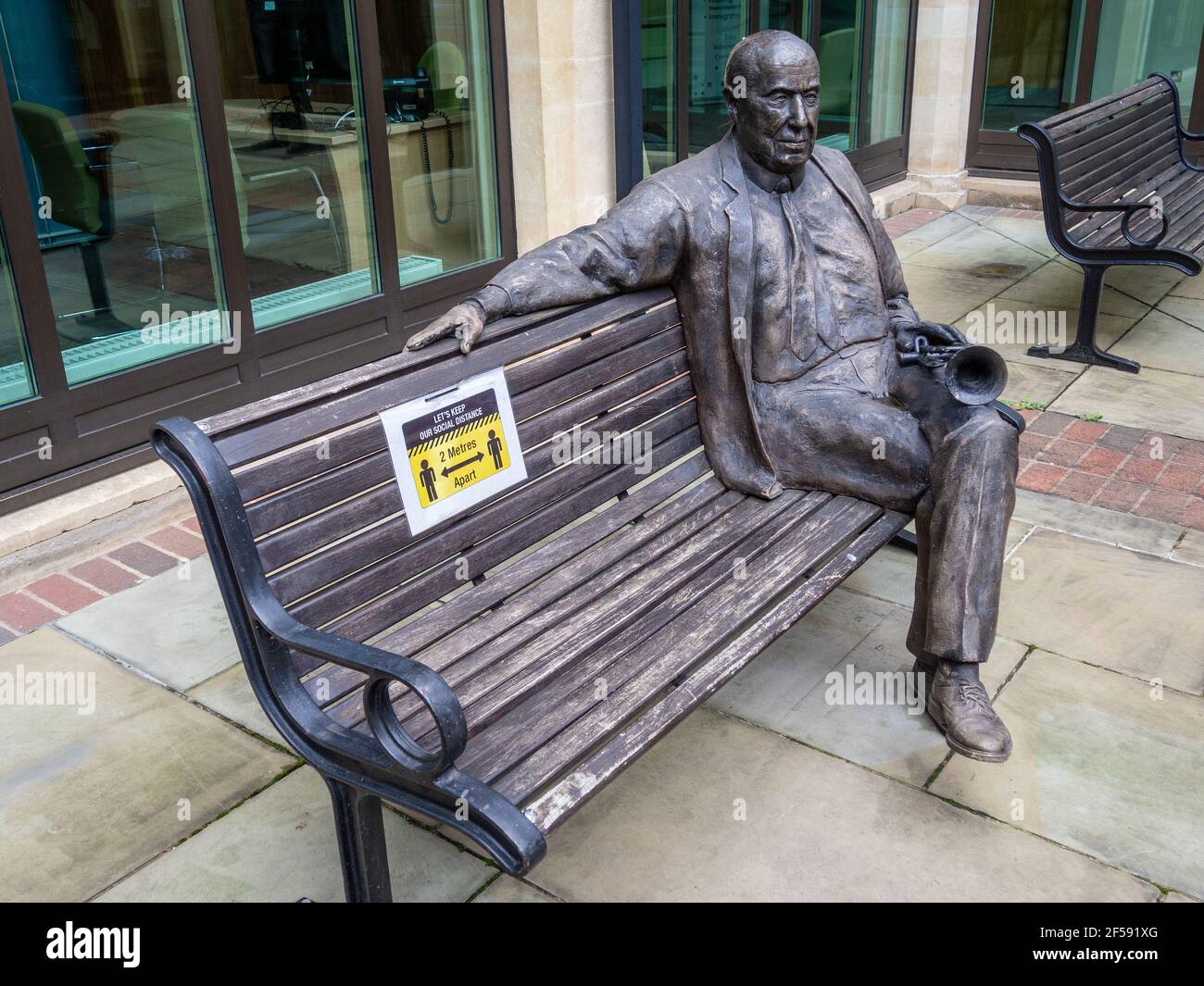 A statue of Malcolm Arnold, the composer, in the Northampton Guildhall.; pictured during the third UK lockdown with adjacent social distancing sign Stock Photo