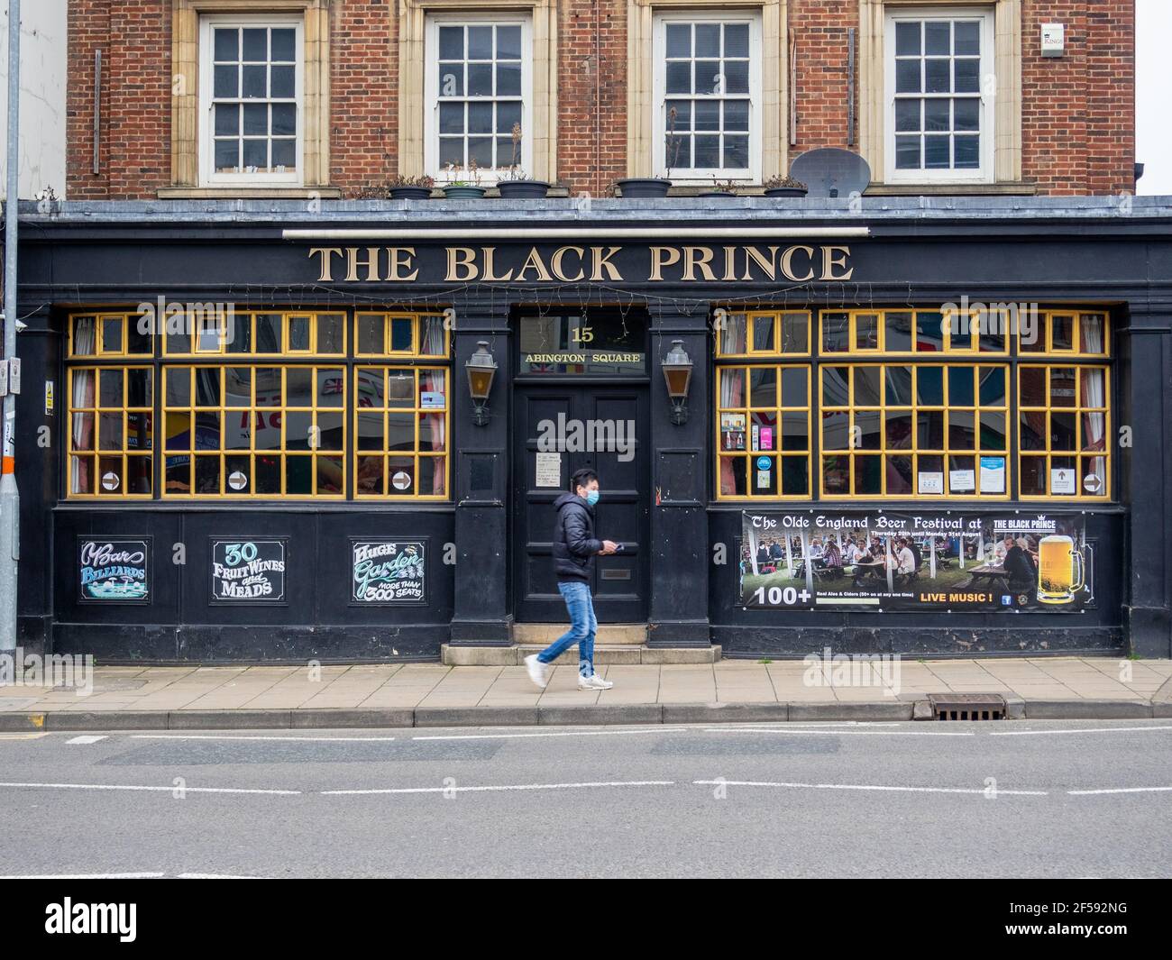 Man in a mask walking past the Black Prince pub, closed during the third UK lockdown, Northampton. Stock Photo