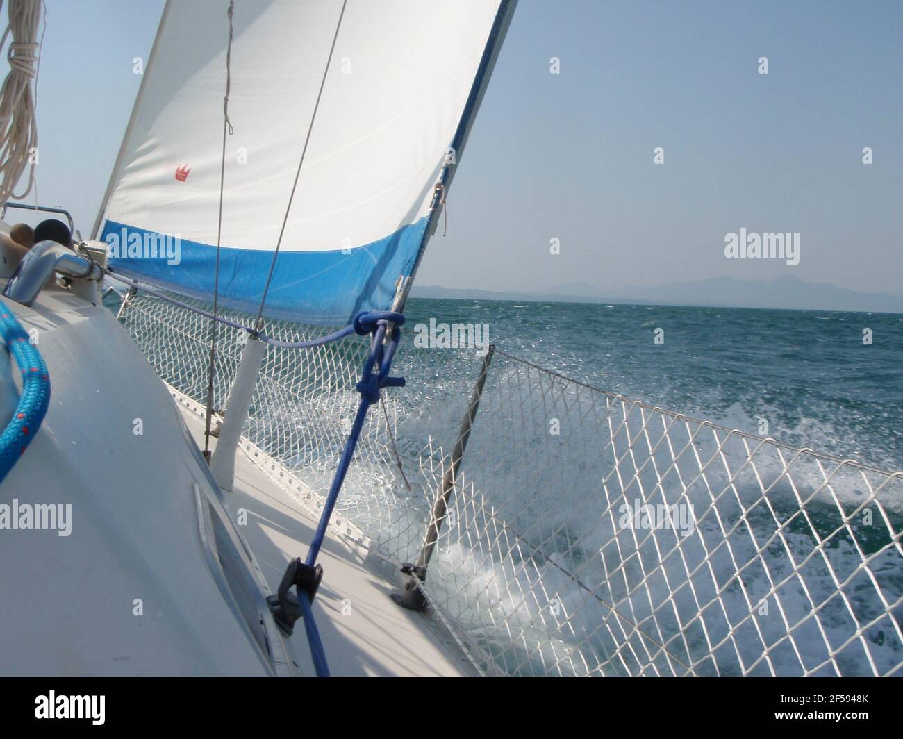 Sailing boat under sail with water splash over guardrail, horizon of ...