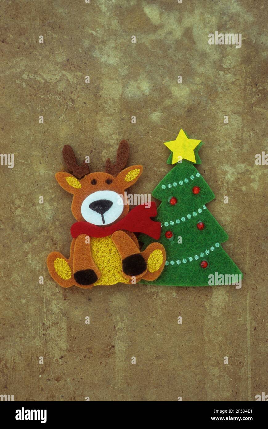 Felt reindeer with friendly face sitting next to Christmas tree Stock Photo